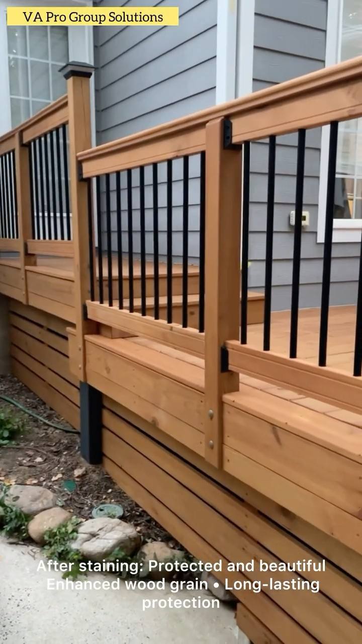 A finished deck after staining, boards and horizontal skirt in a deep brown beneath black balusters