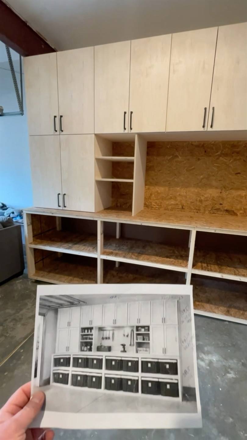 Plywood garage cabinets fitted along a wall above open shelving, with the printed design drawing held up in front of them