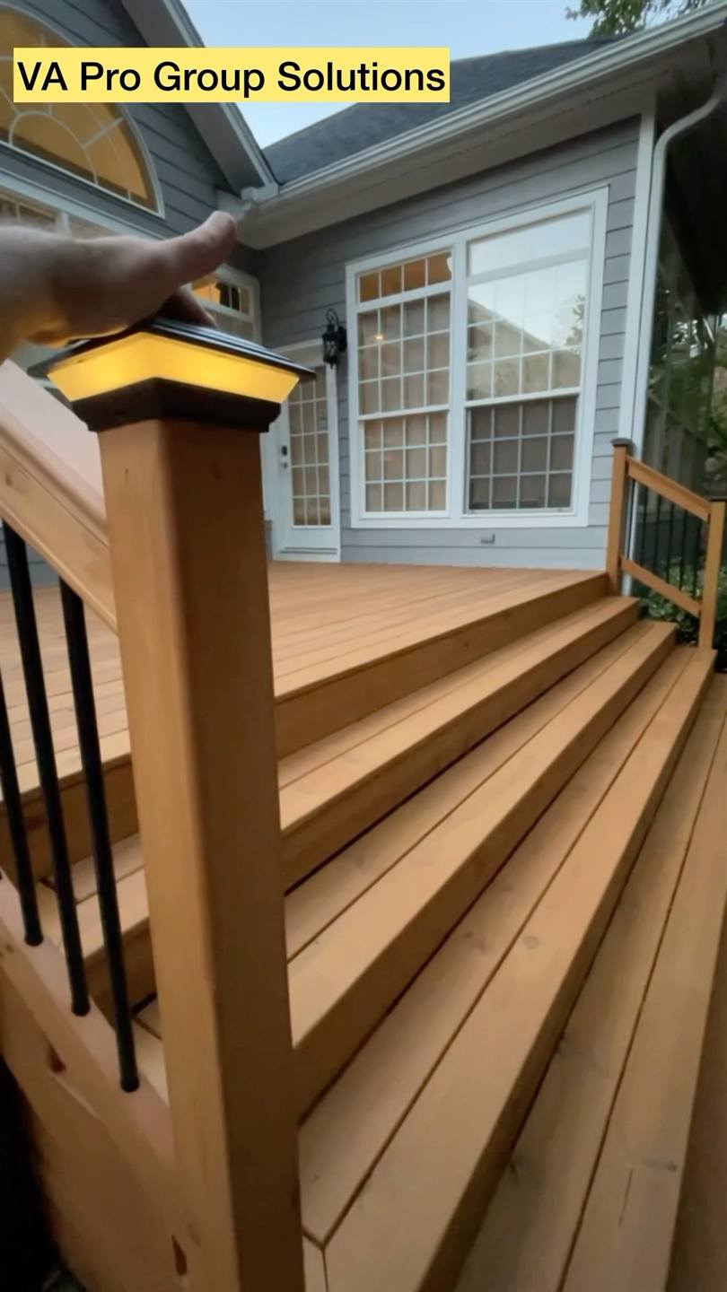 A renovated deck with fresh boards and black metal balusters running down to the steps