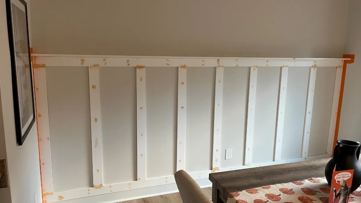 Battens fixed across the wall in bare white, edges masked, before any color goes on