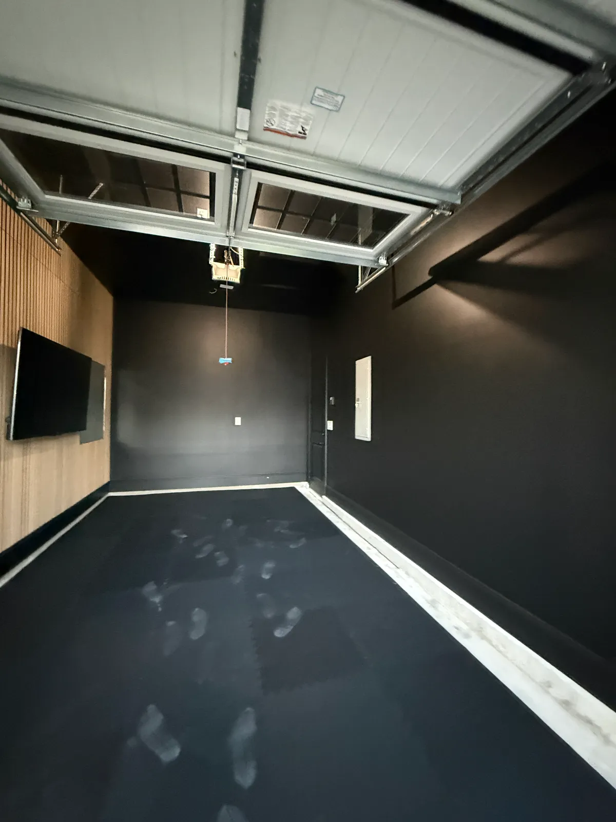 Finished garage room with dark tiled floor and slat wall