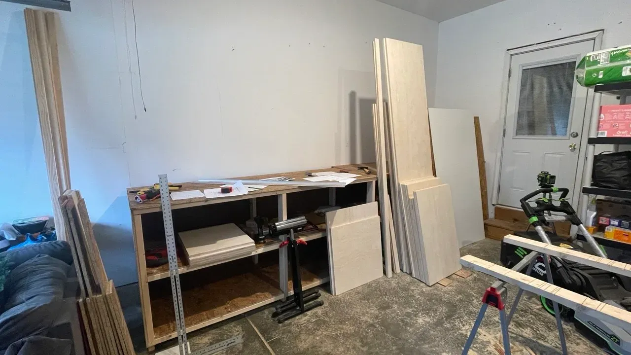 Garage with sheet material stacked beside a part-built bench