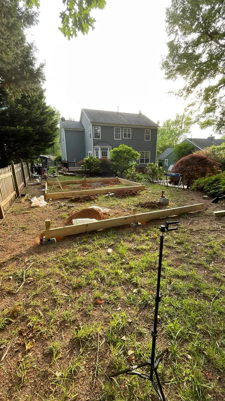 Sloping back lawn with the first treated beams laid out on bearing points