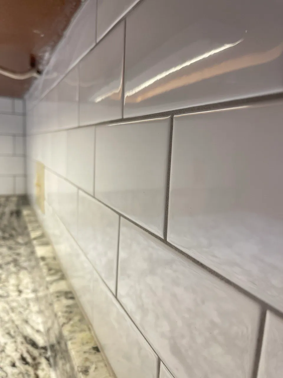 Close raking view along the white subway tile showing the joint lines