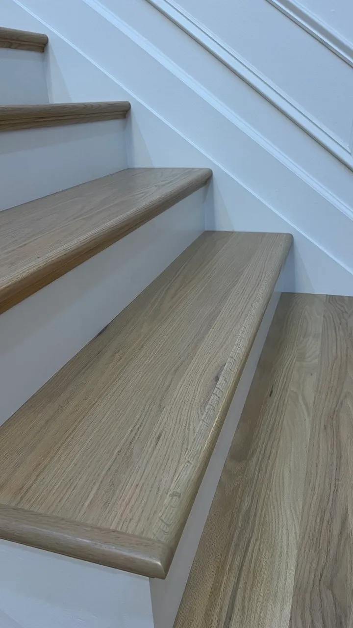 Close view of an oak tread nosing meeting a white riser