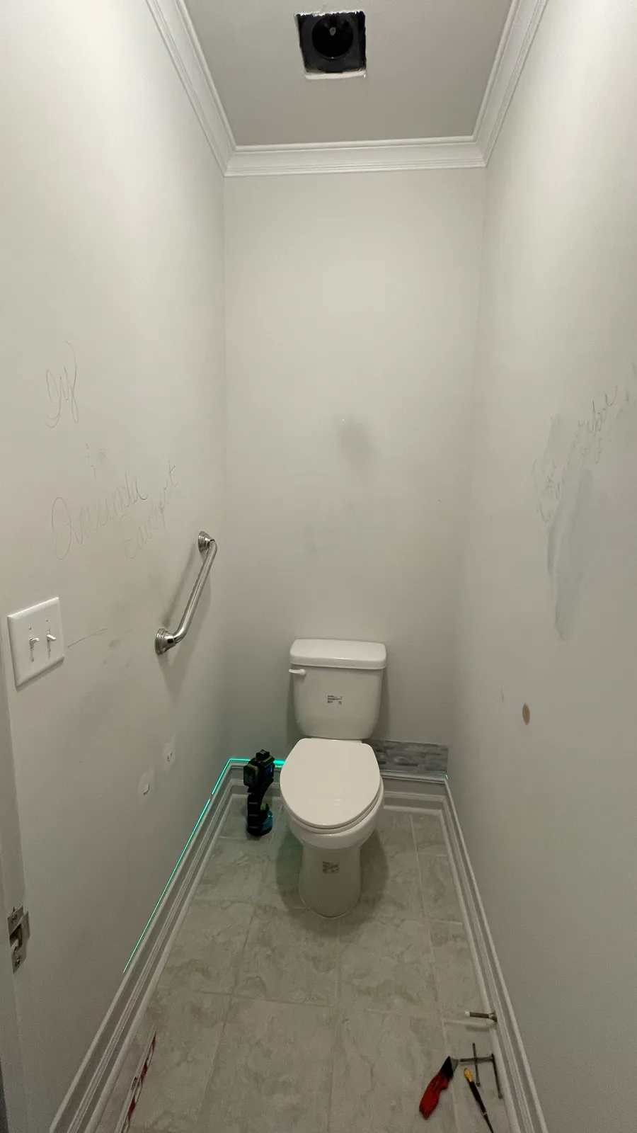 Narrow toilet room with plain white walls and a bare tiled floor