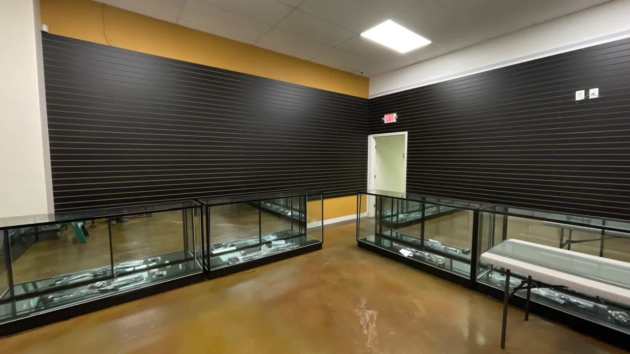 Retail floor with glass display cases in front of the completed dark slat walls