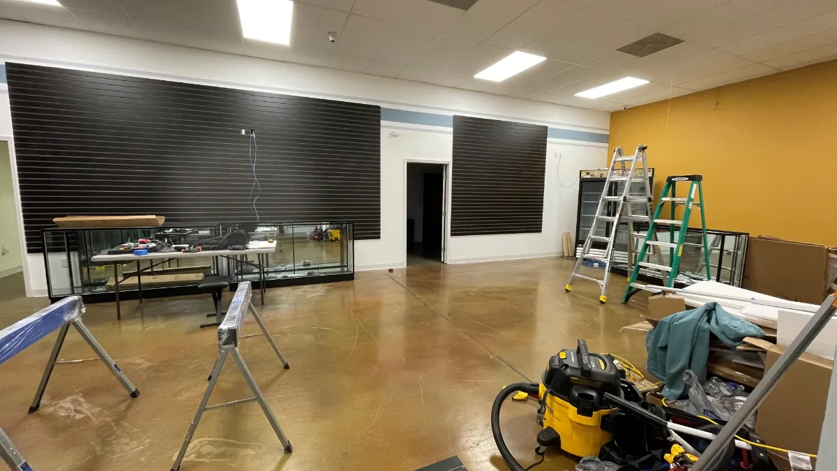 The slat run part-way along the wall, display cases pulled clear and tools on the floor