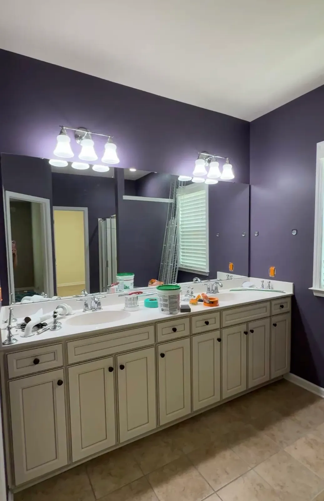 Primary bathroom with dark purple walls and painting materials on the counter