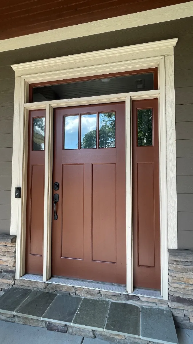 A stained timber front door with glazed panels and matching side lights in a painted surround