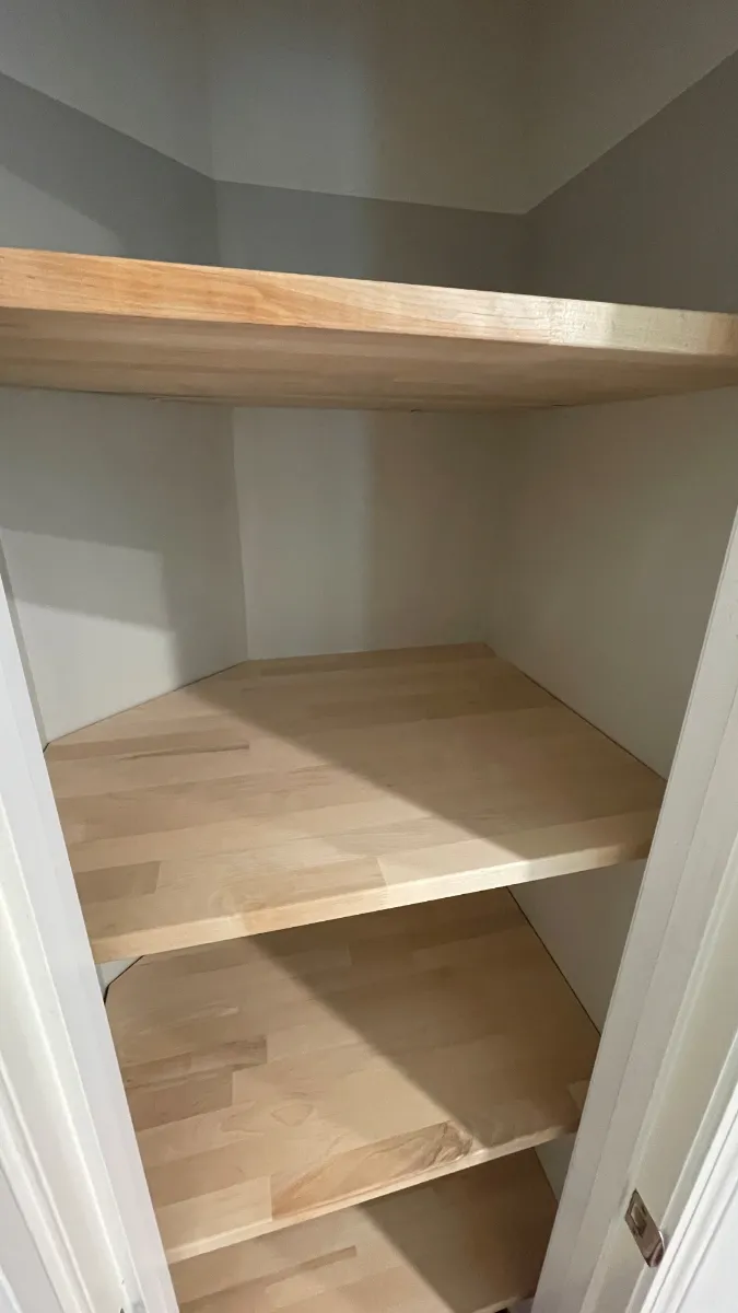Pale timber shelves fitted into a pantry nook and cut to the angle of the wall
