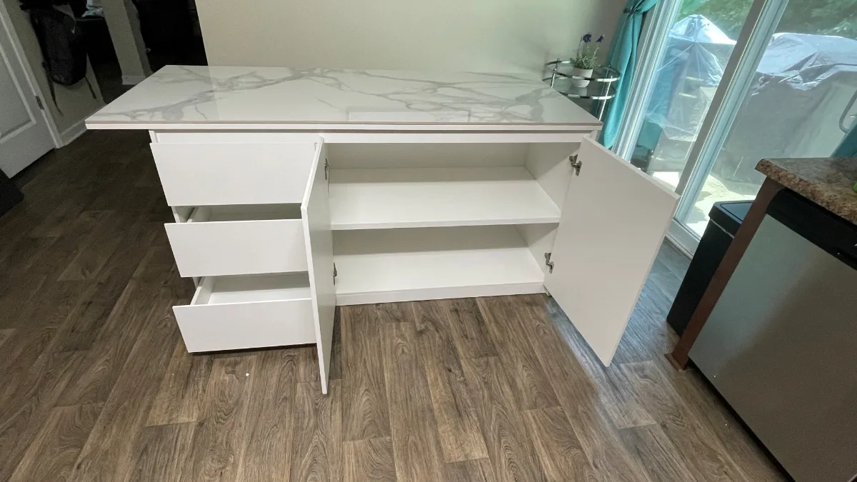A white kitchen island with open shelving and a marble-patterned waterfall top on plank flooring