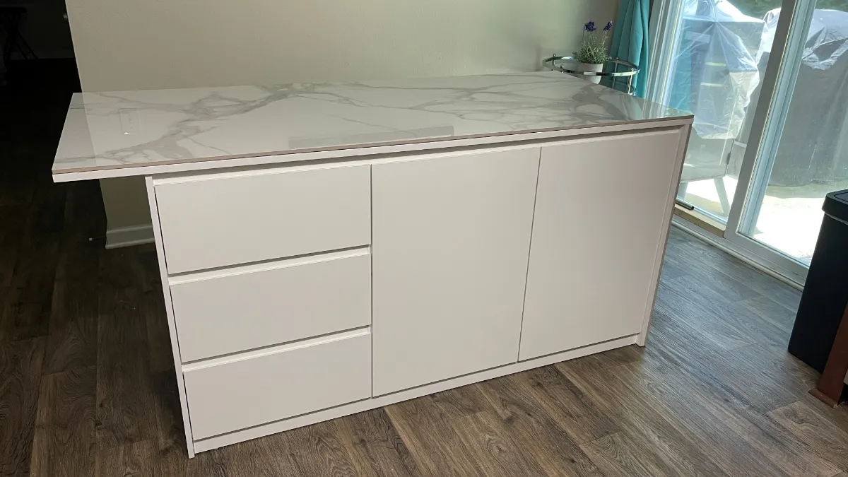 The island from the drawer side, three drawers and a cupboard under a marble-patterned top