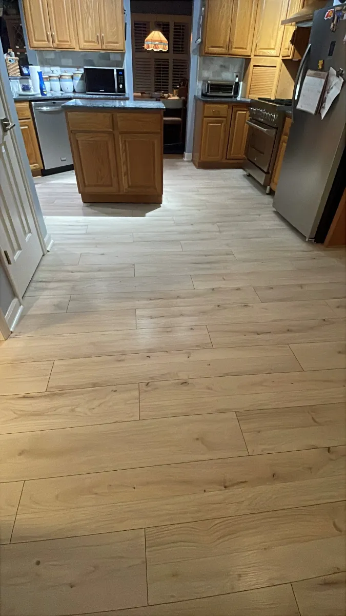 Wide plank flooring run through a kitchen with oak cabinets and stainless appliances