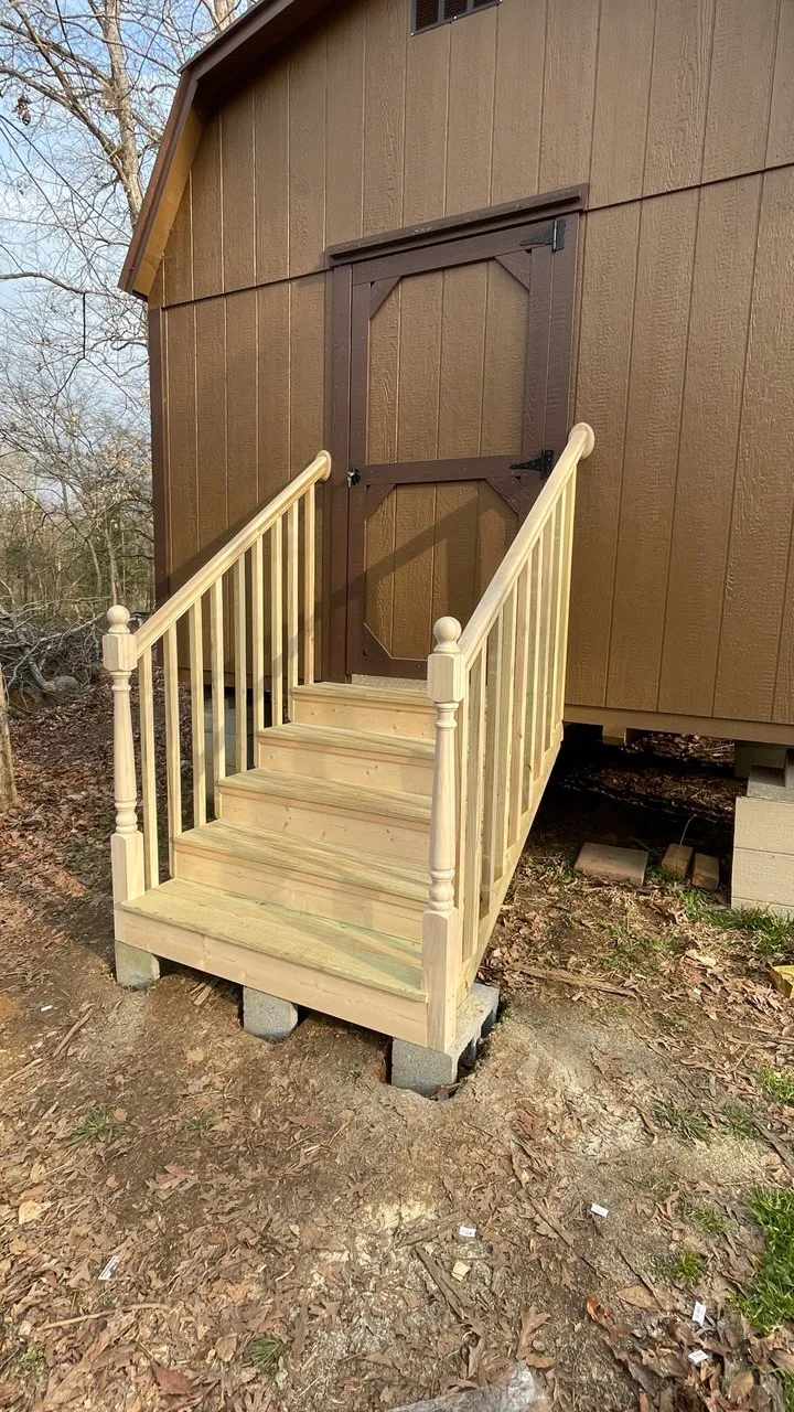 Completed flight of exterior stairs leading up to the outbuilding door, with a full balustrade both sides