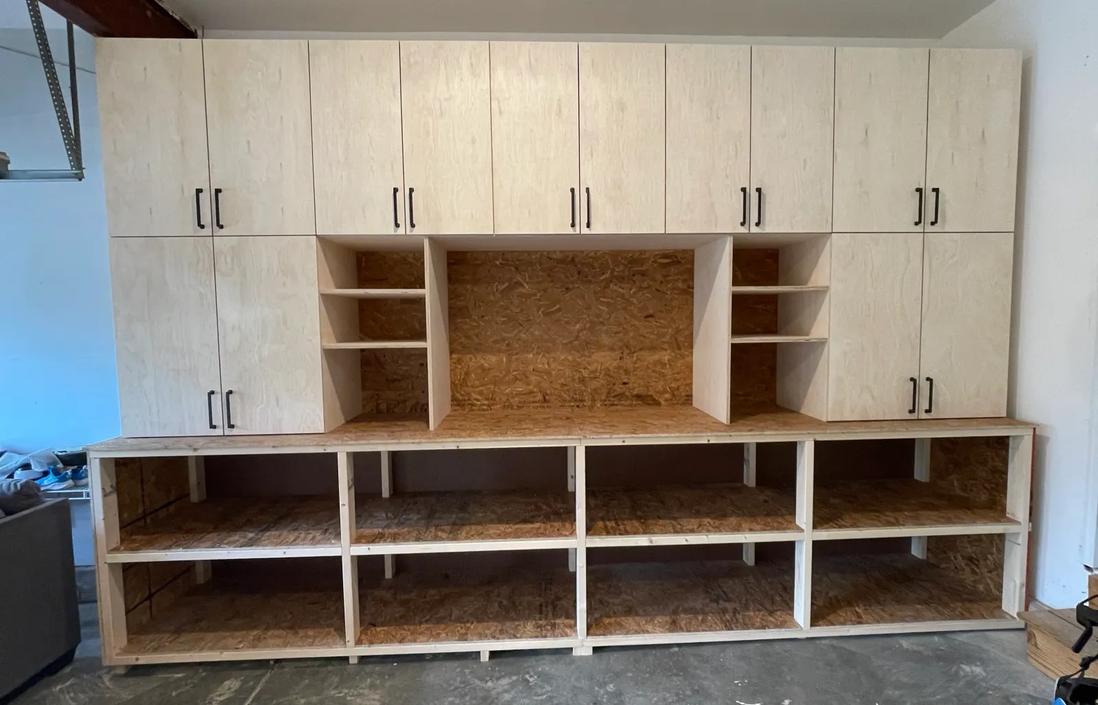 Completed wall of garage cabinets with upper doors, open shelving, and a worktop