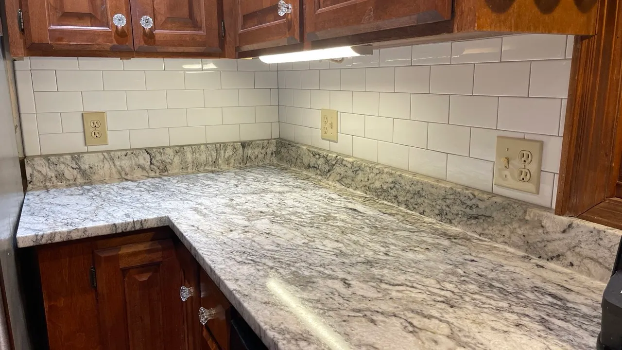 Kitchen corner with granite worktops, a white subway backsplash, and timber wall cabinets