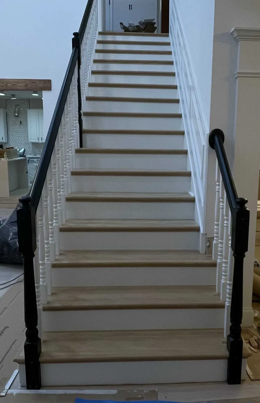 Finished staircase with oak treads, white risers, and a black handrail and newels