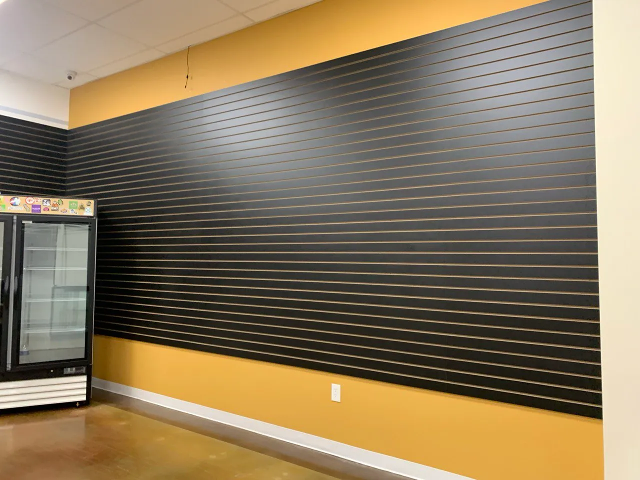 Black horizontal slat wall running the length of a retail space above a yellow base